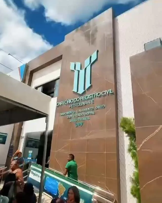 Fachada da sede do cartório, revestida em pedra, com as colunas turquesa do logo